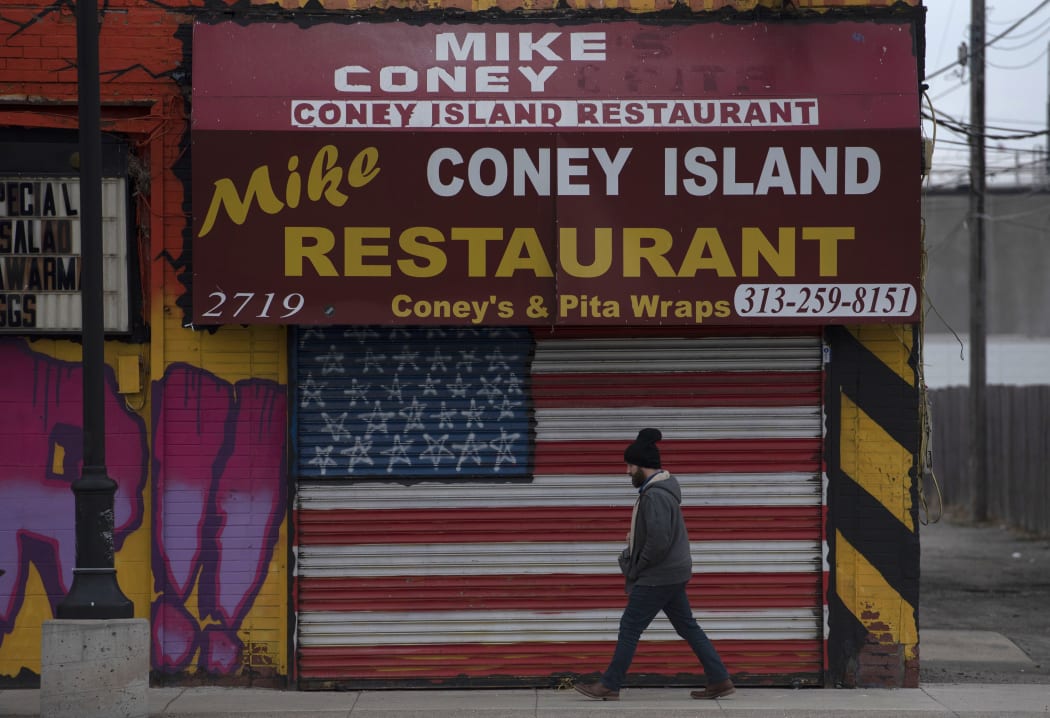 A man passes a closed restaurant near the Eastern Markets in Detroit, Michigan on 24 March 2020.