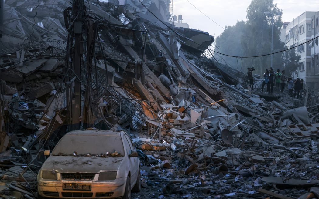 A damaged car sits amid the rubble of a tower destroyed in an Israeli air stike in Gaza City on October 7, 2023. Palestinian militants have begun a "war" against Israel which they infiltrated by air, sea and land from the blockaded Gaza Strip, Israeli officials said, a major escalation in the Israeli-Palestinian conflict. (Photo by MOHAMMED ABED / AFP)