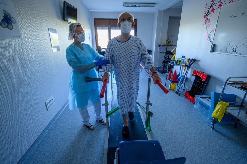 A physiotherapist helps a patient in rehabilitation as he recovers from Covid-19, at a hospital in eastern France, on 14 April, 2020.