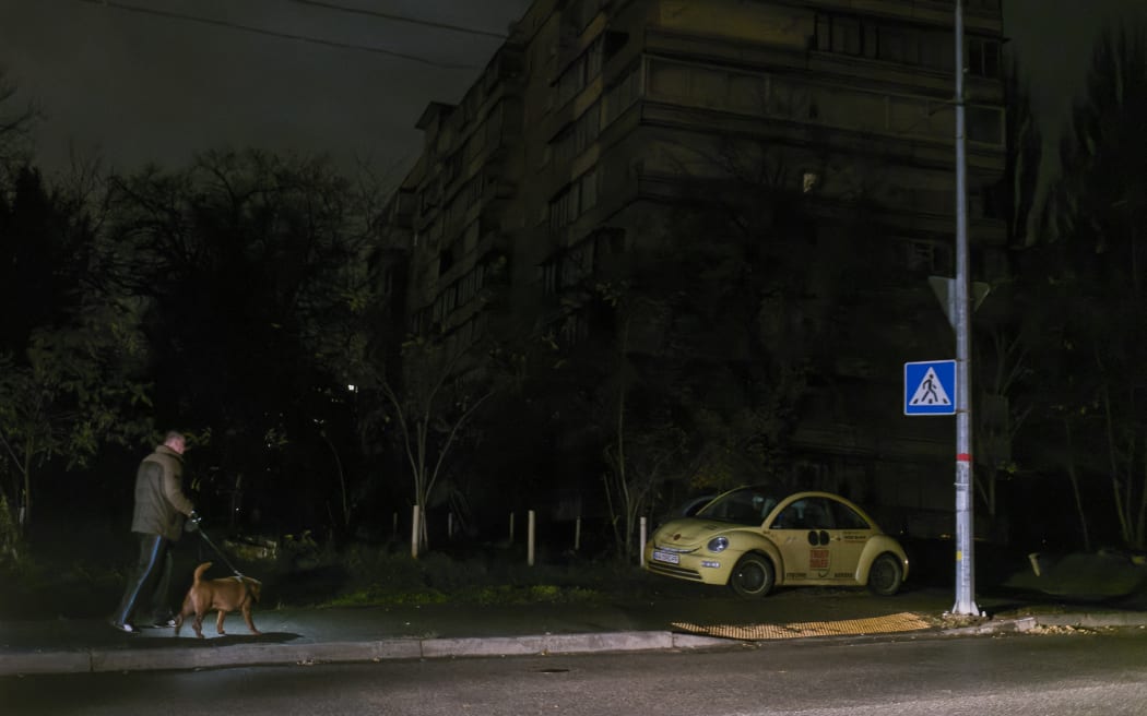 A man walks a dog along during a blackout after a Russian missile attack on Ukrainian power infrastructure in Kyiv, Ukraine, 3 November 2022