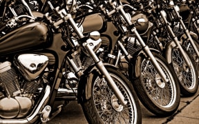 Sepia tone photograph of similar style motorcycles parked side by side.