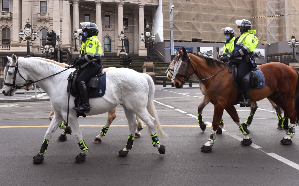 Police on horseback patrol the Melbourne central business district on August 9, 2020, as the city struggles to cope with a COVID-19 coronavirus outbreak.