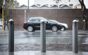 Rain pours down as cars drive by.