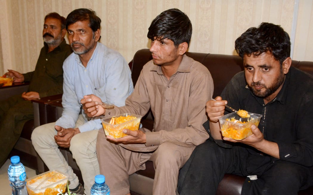 Train passengers eat food at the deputy commissioner office in Quetta on March 12, 2025,  after escaping the siege claimed by the Baloch Liberation Army (BLA). Pakistan security sources said on March 12 the military had freed 190 train passengers taken hostage by gunmen as a deadly siege in the mountainous southwest stretched through its second day. (Photo by AFP)