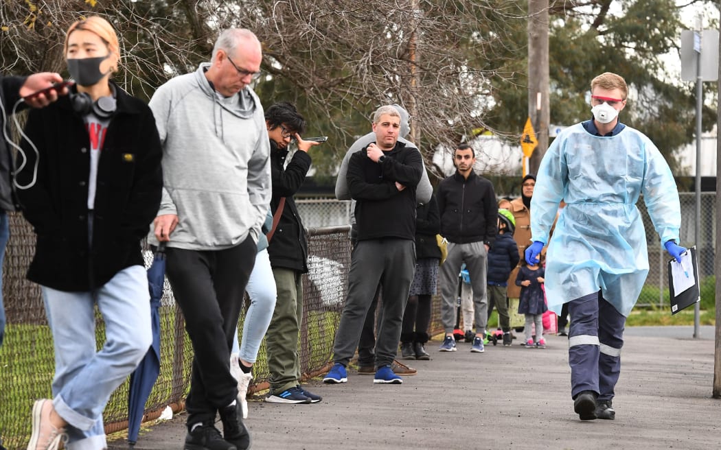 A health worker (R) takes details as people queue during COVID-19 coronavirus testing in a park in the Melbourne suburb of Brunswick West on July 2, 2020.
