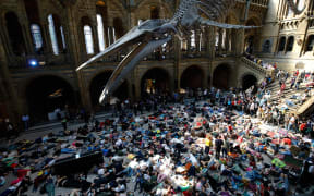 Extinction Rebellion climate change activists perform a mass "die in" under the blue whale in the foyer of the Natural History Museum.