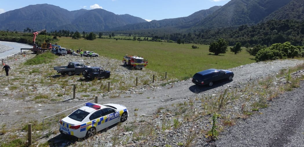 A hearse carrying the bodies of two tourists leaves the Wanganui River bank.