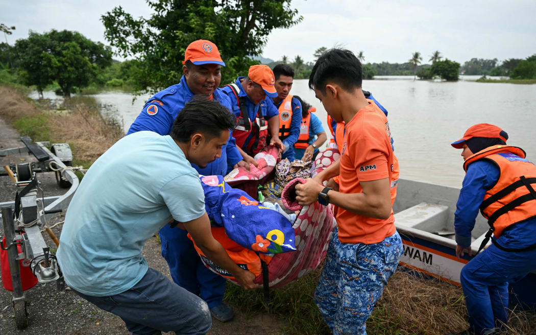 Rescue workers carry an elderly woman needing medical attention from a boat after evacuating her from a flooded home in Kangar in northern Malaysia's Perlis state on November 27, 2025.