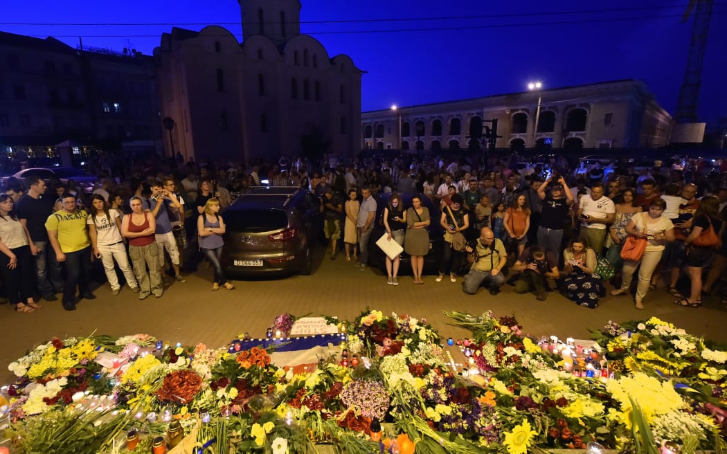 People gather near flowers and candles placed in front of the Embassy of the Netherlands in Kiev.