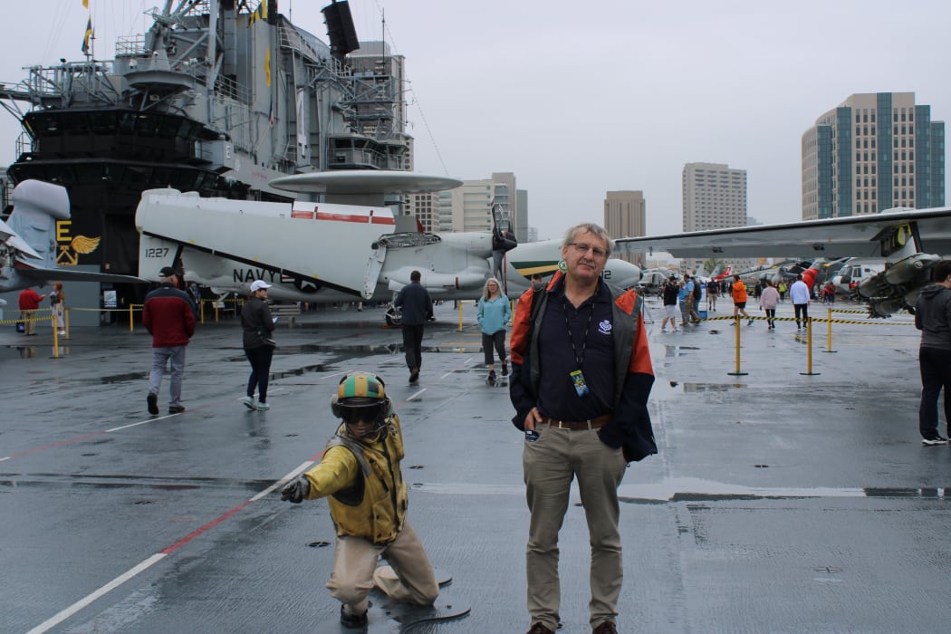 Leo Schepp standing in the very large hanger of the aircraft carrier Midway, that is now a floating museum in San Diego.