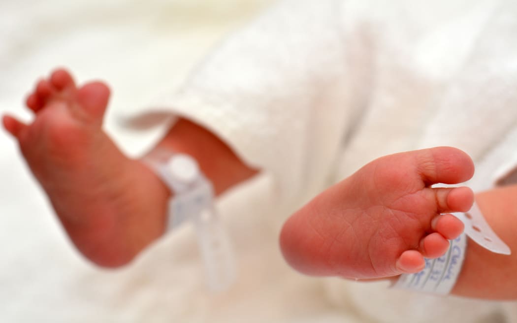 Newborn baby feet with identification bracelet tag name.