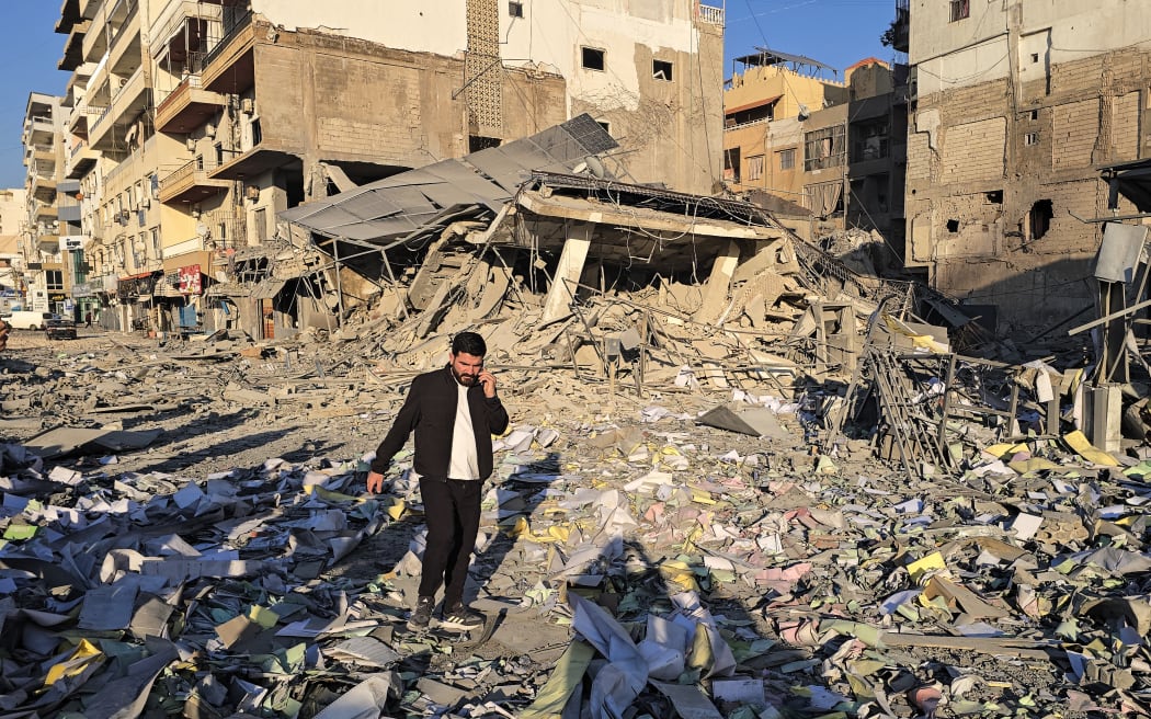 A man makes his way through debris at the site of an Israeli airstrike that targeted the offices of Al-Qard al-Hassan, a Hezbollah-linked financial institution, in the southern coastal Lebanese city of Tyre on March 2, 2026. Israel bombarded Lebanon on March 2, expanding the conflict across the region after the massive Israel-US attack on Iran that the US president launched to topple Tehran's ruling clerics, and killing their supreme leader o February 28. (Photo by KAWNAT HAJU / AFP)