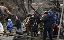People cross a destroyed bridge as they  evacuate the city of Irpin, northwest of Kyiv, during heavy shelling and bombing on March 5, 2022, 10 days after Russia launched a military invasion of Ukraine.