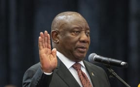 South African President Cyril Ramaphosa raises his hand as he is sworn is as a member of Parliament ahead of an expected vote by lawmakers to decide if he is reelected as leader of the country in Cape Town, South Africa, Friday, June 14, 2024. (AP Photo/Jerome Delay)