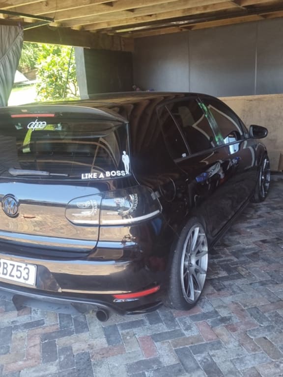 The car - with a license plate RBZ53 - is a dark coloured hatchback.