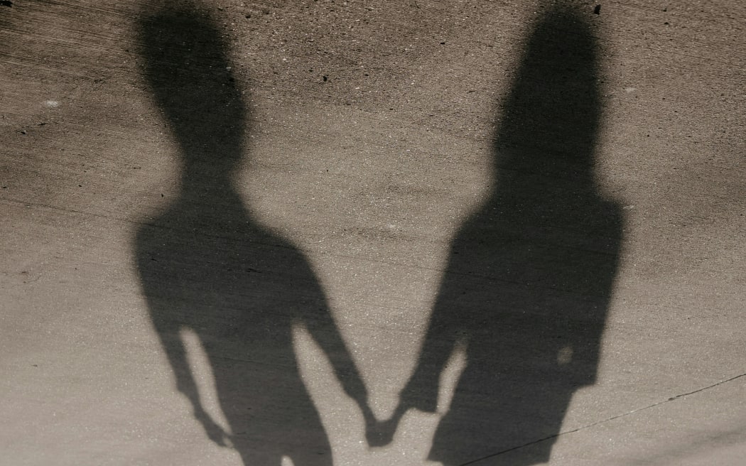The shadows of two people hold hands.