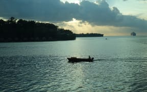 A boat crosses Port Vila habour at sunset.