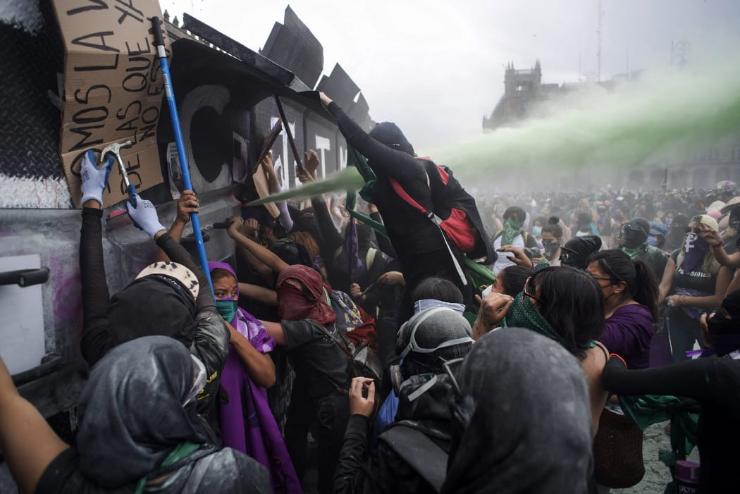 Women try to pull down a security fence during a demonstration to commemorate the International Women's Day in Mexico City.