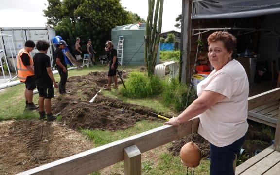 Home-owner Atholene Ngauma watches as the Tupu Plumbing team install her rainwater tank.
