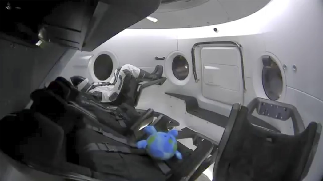 This photo provided by SpaceX shows a life-size test dummy along with a toy that is floating in the Dragon capsule as the capsule made orbit on Saturday, March 2, 2019.