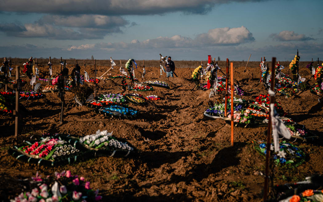 A cemetery worker carries a memorial cross during the burial of Ukranian Olena Afanasievska, who was killed in a Russian missile attack on 24 December, at a funeral ceremony in the southern city of Kherson on 28 December , 2022.