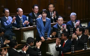 Liberal Democratic Party (LDP) President Sanae Takaichi stands up to acknowledge the applause after she was selected as Japan's new prime minister during an extraordinary session of the lower house of parliament in Tokyo on October 21, 2025.  (Photo by Philip FONG / AFP)