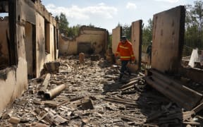 Firefighters work among the ruins of a house, which is said was hit by Azeri shelling during recent border clashes with Azerbaijan, in the settlement of Sotk, Armenia.