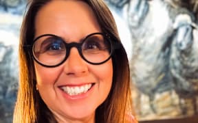This is a close up head shot of Cally Whitman. She is smiling and wearing round, black framed glasses.