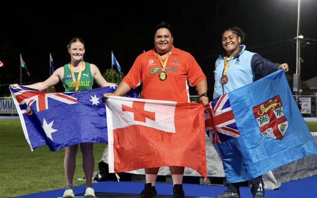Tonga's Ata Ma'ama Tu'utafaiva, middle, proudly shows her country's flag and gold medal along with silver medalist Taylor Laarson of Australia. left, and Fiji's Maryann Macedru.