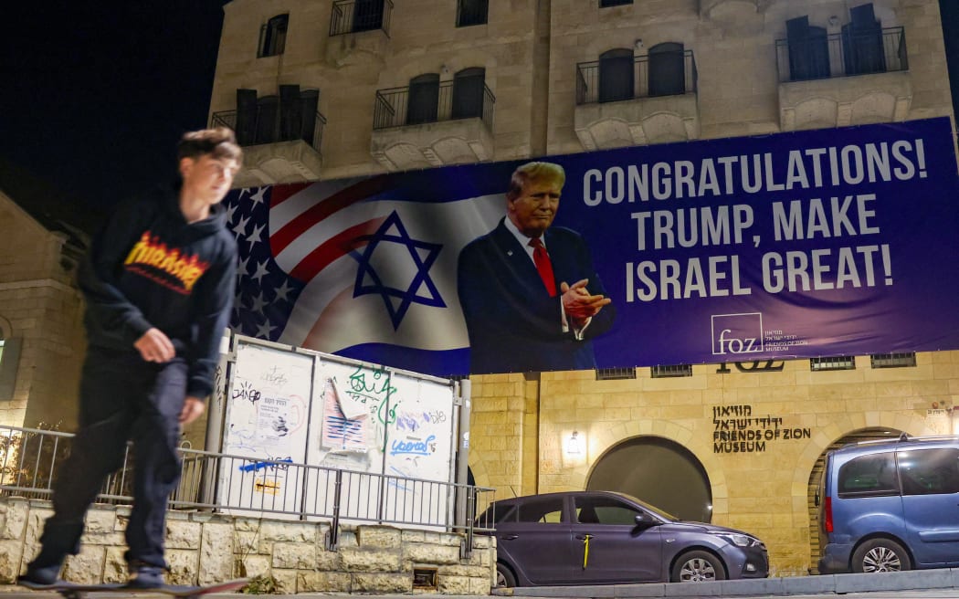 A youth skateboards under a banner congratulating US President-elect Donald Trump on winning the US presidential election, in Jerusalem on November 7, 2024. - Israeli Prime Minister Benjamin Netanyahu on November 6 congratulated Donald Trump, who has won the US presidential election, calling it "history's greatest comeback" and a new beginning in the US-Israel alliance. (Photo by Ahmad GHARABLI / AFP)
