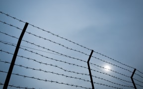 Silhouette of barbed wire on the fence of detention center.