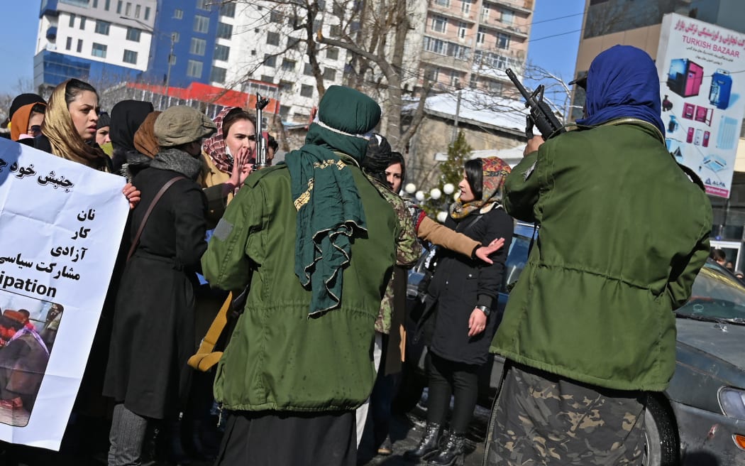 Taliban fighters trying to control women as they chant slogans during a protest demanding for equal rights, along a road in Kabul on 16 December, 2021.