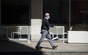 A man with a mask walks through downtown Houston, Texas after Texas Governor Greg Abbott announced he was lifting a mask mandate and that all businesses will be allowed to open at 100 percent beginning March 10.