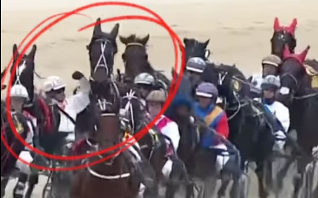 Harness-racing driver Jonny Cox can be seen punching the trailing horse as it got too close to him.