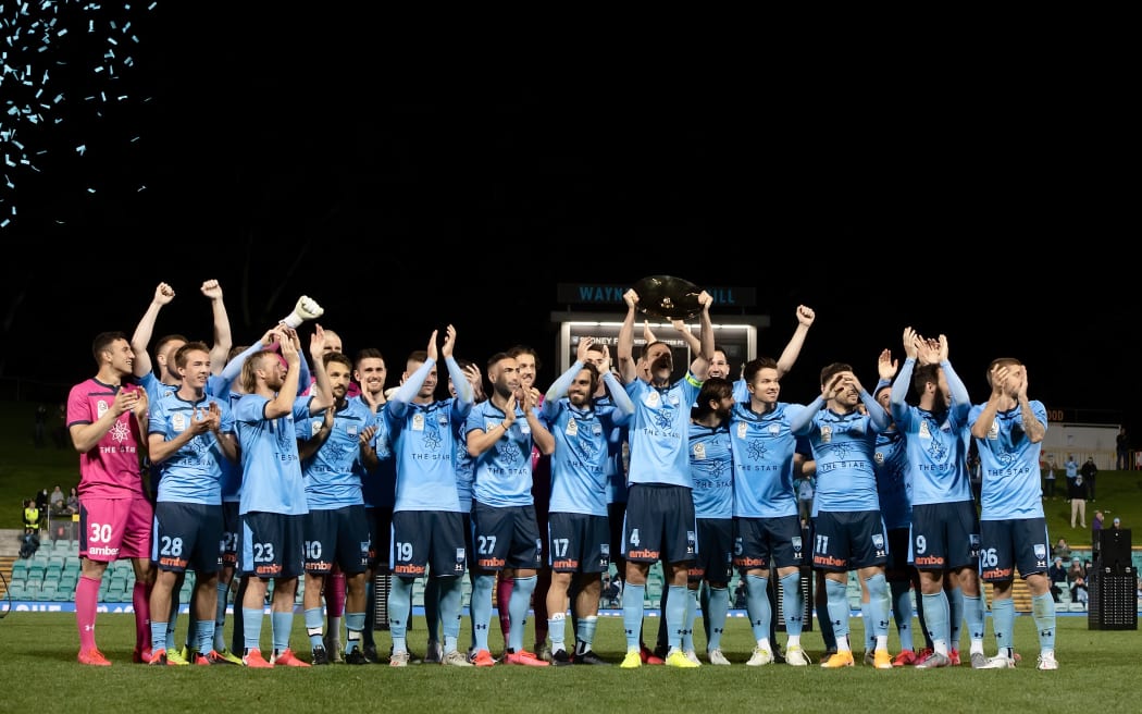 Sydney FC captain Alex Wilkinson  holds up the Premier's Plate 2020.