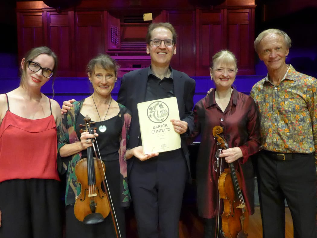 Pianist Denes Varjon and the New Zealand String Quartet pose on stage following their performance of the Piano Quintet by Bela Bartok at the 2024 Adam Chamber Music Festival. Denes holds the score.