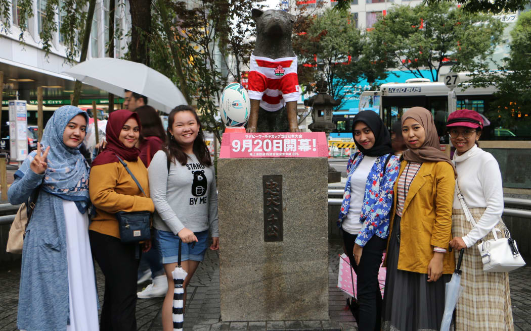 Tourists pose with the Hachiko statue in Tokyo.