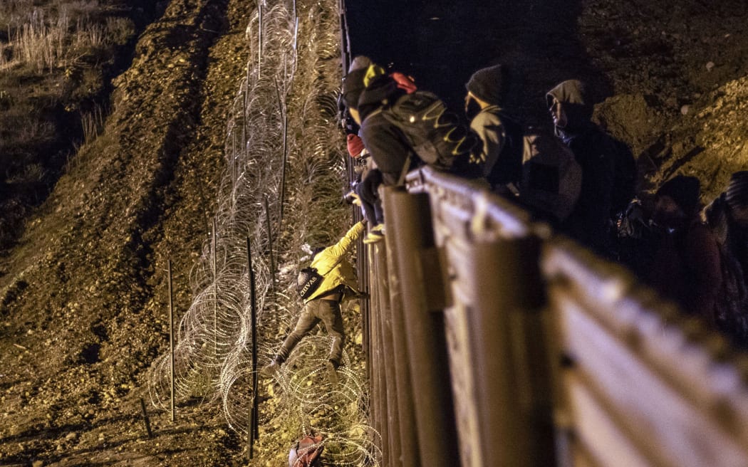 A Central American migrant jumps over the US-Mexico border fence from Tijuana to San Diego in the US