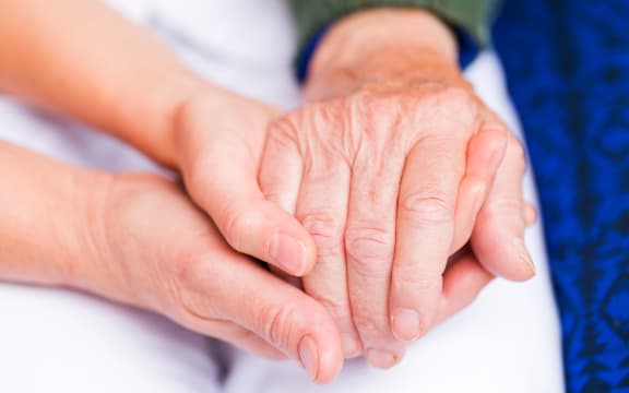 Carer giving helping hands for elderly woman.
