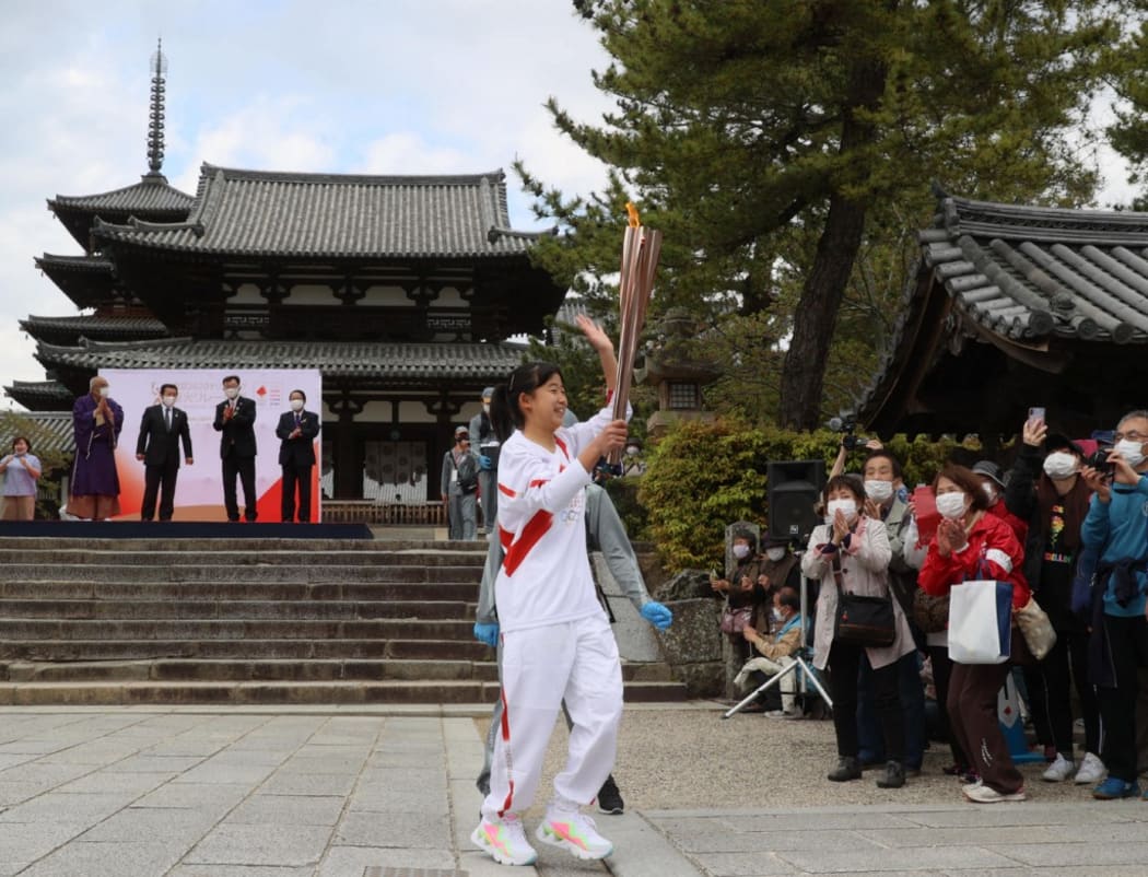 Torch bearer carrying an Olympic flame arrives at Horyu-ji, UNESCO World Heritage site Buddhist temple, in Ikaruga Town, Nara Prefecture on April 12, 2021.