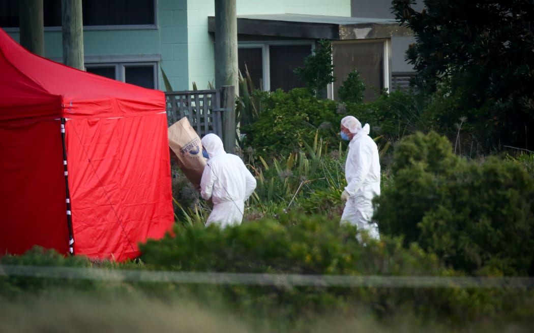Police forensics taking a bag of evidence back to the tent.