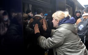 A woman says goodbye as a train with evacuees is about to leave Kyiv's railway station on March 2, 2022. Russia steps up its bombing campaign and missile strikes on Ukraine's cities on March 2, 2022.