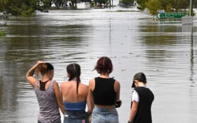 Residents stand by a flooded street in Lawrence suburb, some 70 kilometres New South Wales border city Lismore, on March 1, 2022. (Photo by SAEED KHAN / AFP)