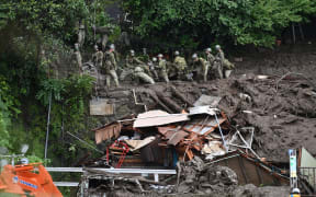 Members of Japan's Self-Defense Forces sift through mud and debris as they search for missing people at the scene of a landslide in Atami on 5 July, 2021.