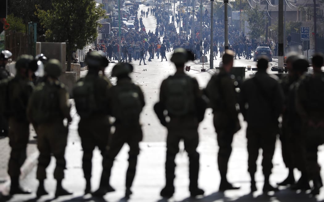 Israeli forces keep watch as and Palestinian protestors throws stones and shout slogans near an Israeli checkpoint.