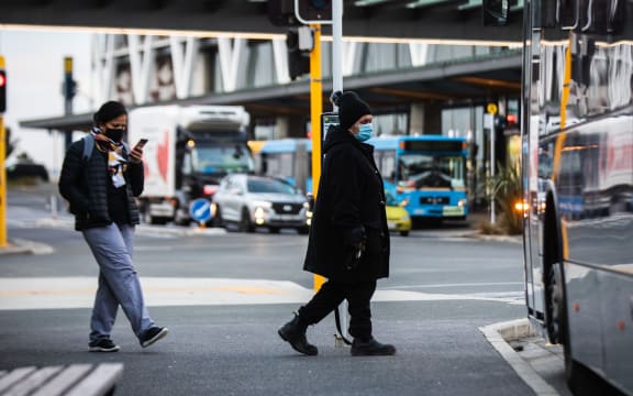 Commuters wearning masks board a bus Manukau