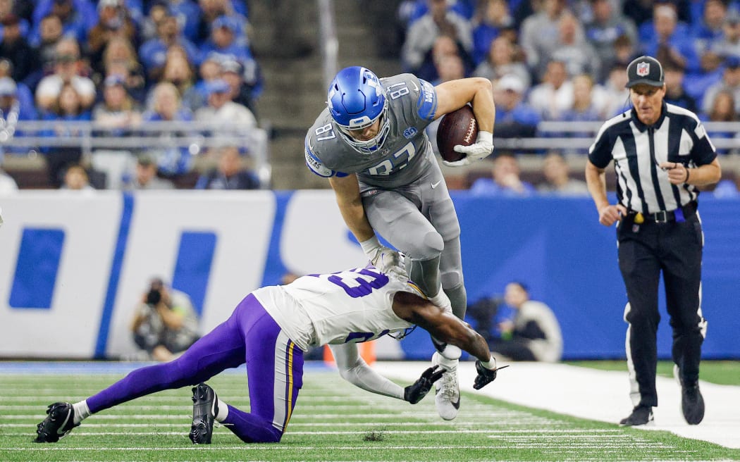 Sam LaPorta #87 of the Detroit Lions is tackled by Andrew Booth Jr. #23 of the Minnesota Vikings.