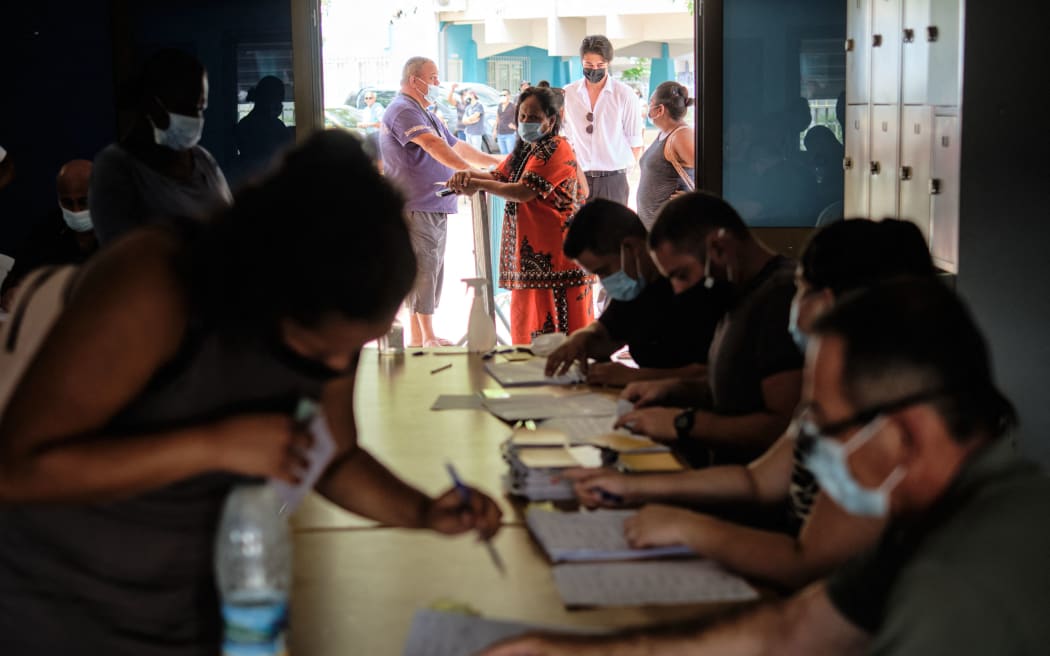 People prepare to casts their ballot for the referendum on independence at a polling station of the City Hall in Noumea, on the French South Pacific territory of New Caledonia on December 12, 2021.