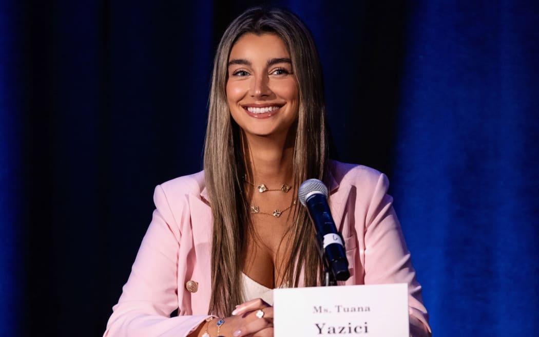 Tiana Yazici, Founder, Chair & CEO of Nonprofit AeroAI Global Solutions, standing in front of a wall of flags.
