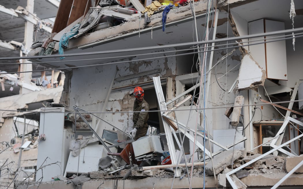 A responder works in a damaged building following a strike by an Iranian missile in the Israeli city of Bat Yam, south of Tel Aviv, early on June 15, 2025. Air raid sirens and booms rang out in Jerusalem and Tel Aviv early on June 15, AFP journalists said, as Israel and Iran exchanged fire for a third day. (Photo by Jack GUEZ / AFP)